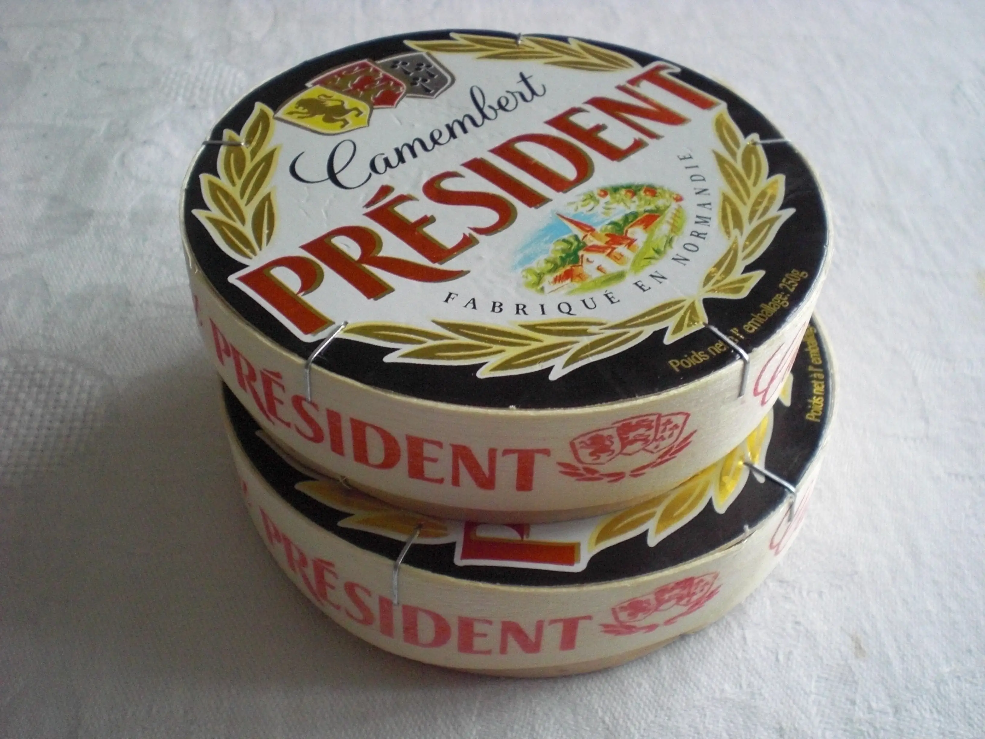 Dos cajas redondas de camembert Président apiladas sobre una tela blanca