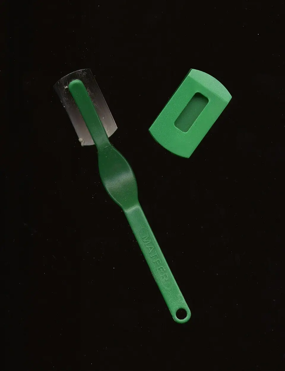 Cuchilla de panadero de mango verde y hoja curva junto a su protector sobre fondo negro