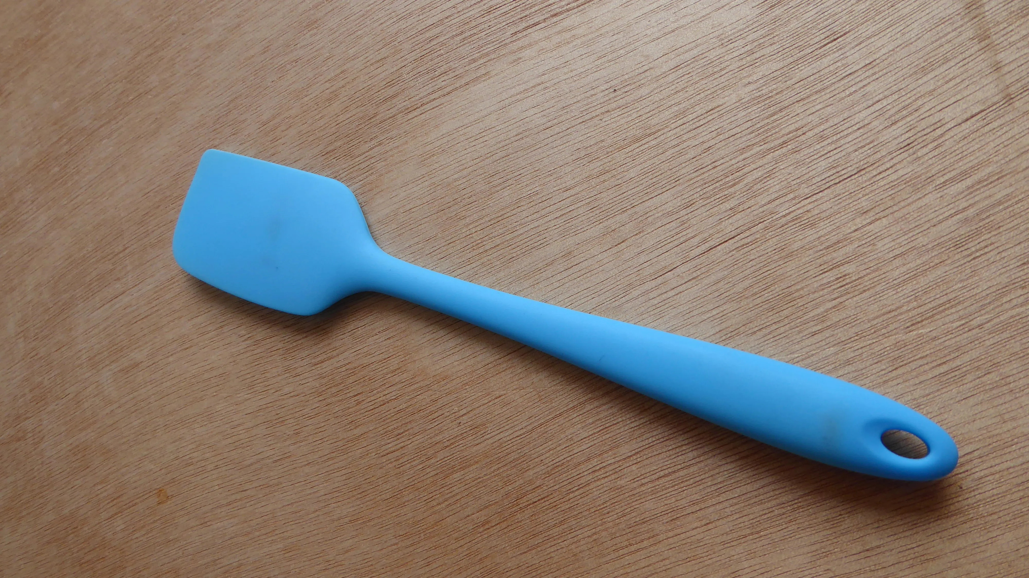 Espátula azul de una pieza sobre una superficie de madera