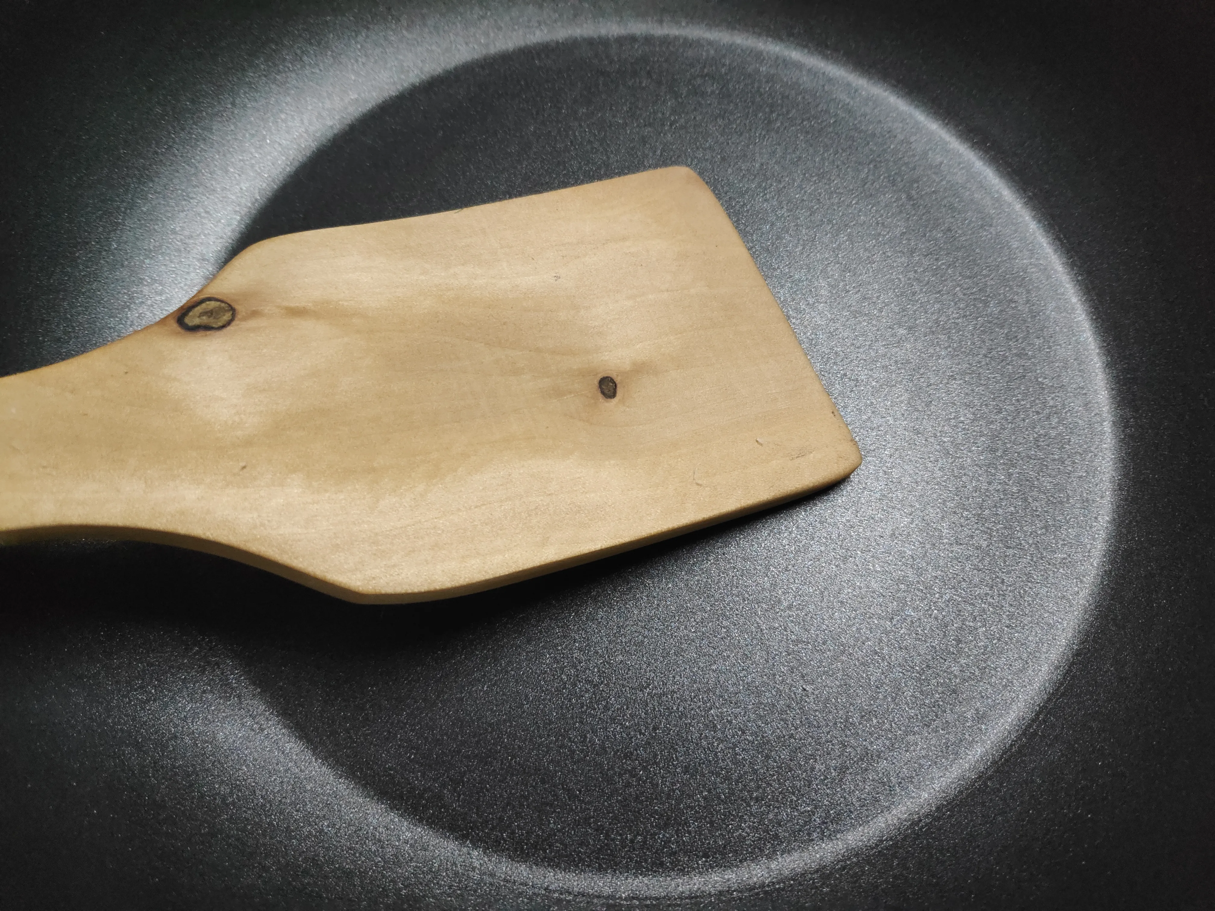 Pala de madera sobre una sartén revestida