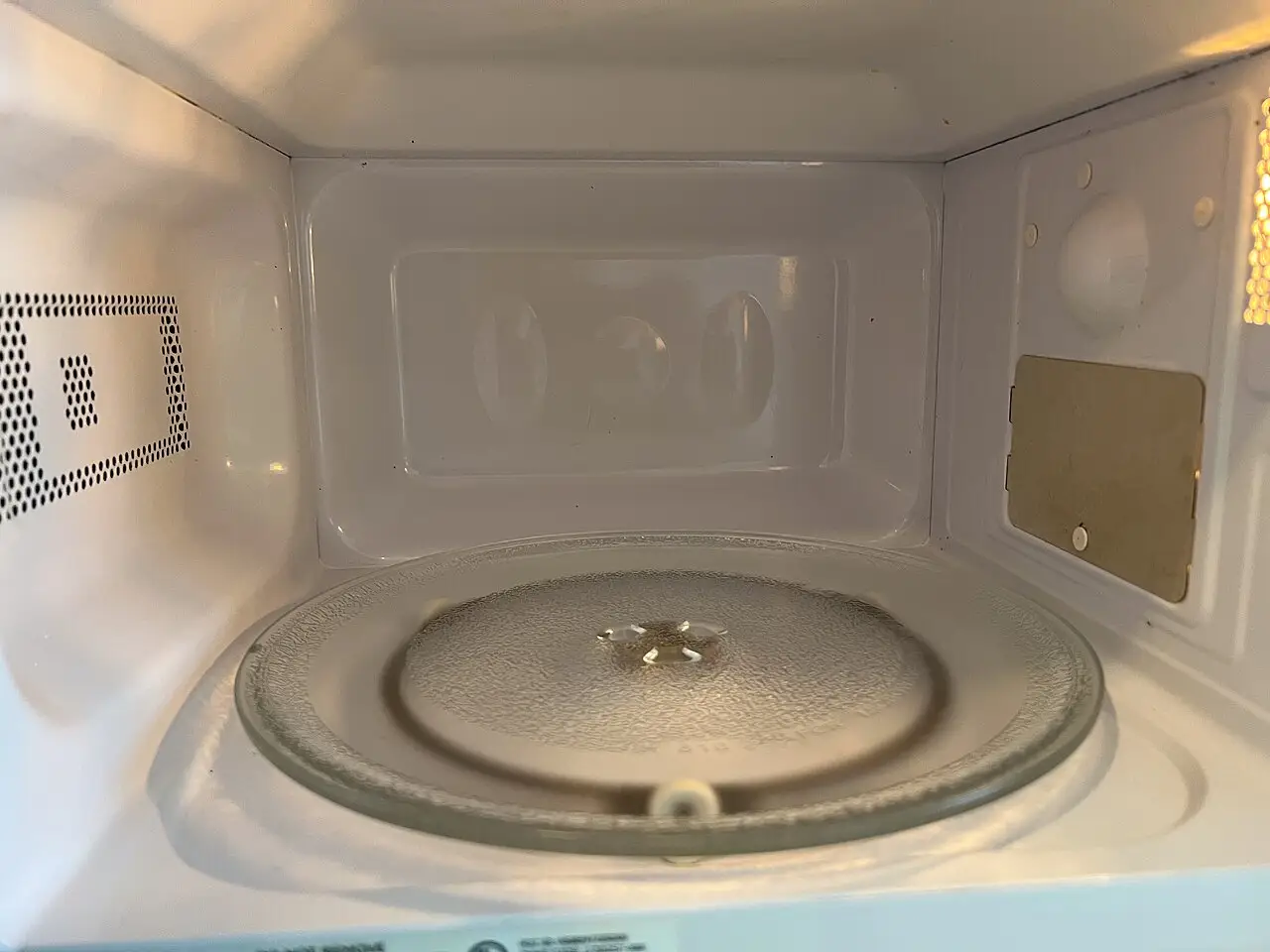 Interior de un microondas doméstico vacío con plato giratorio de vidrio