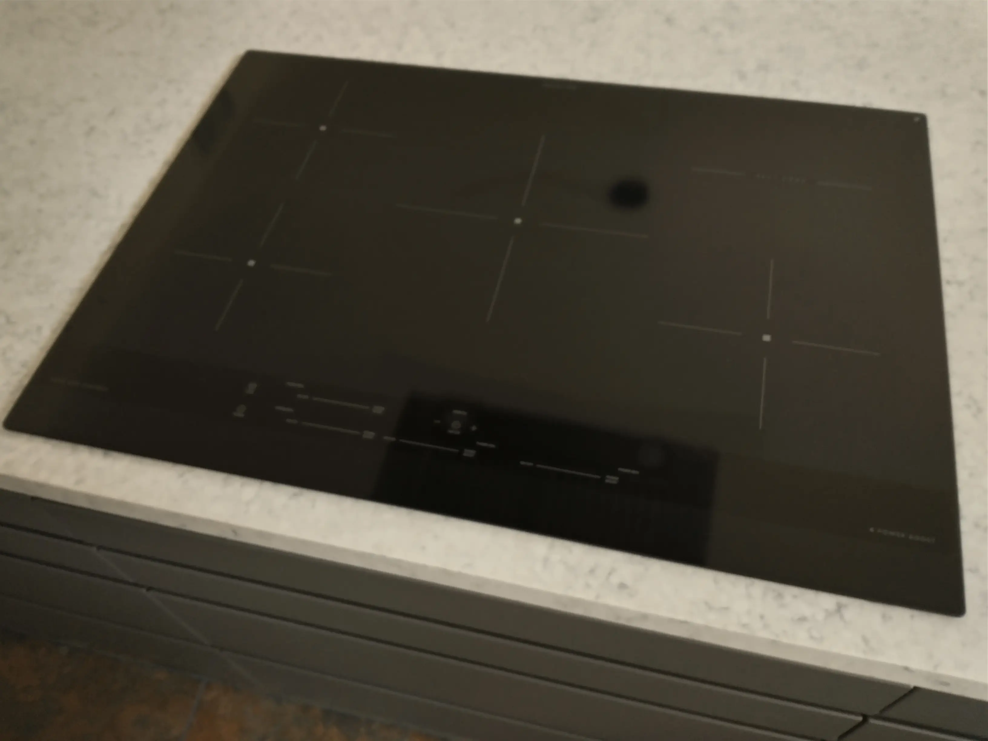 Placa de inducción doméstica con cuatro zonas delimitadas sobre una encimera clara