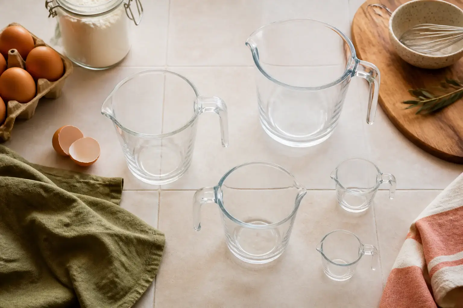 Qué jarra medidora de vidrio comprar representada con utensilios genéricos en una cocina doméstica