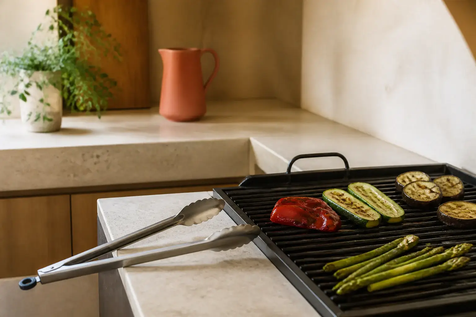 Pinzas largas genéricas junto a verduras sobre una parrilla apagada